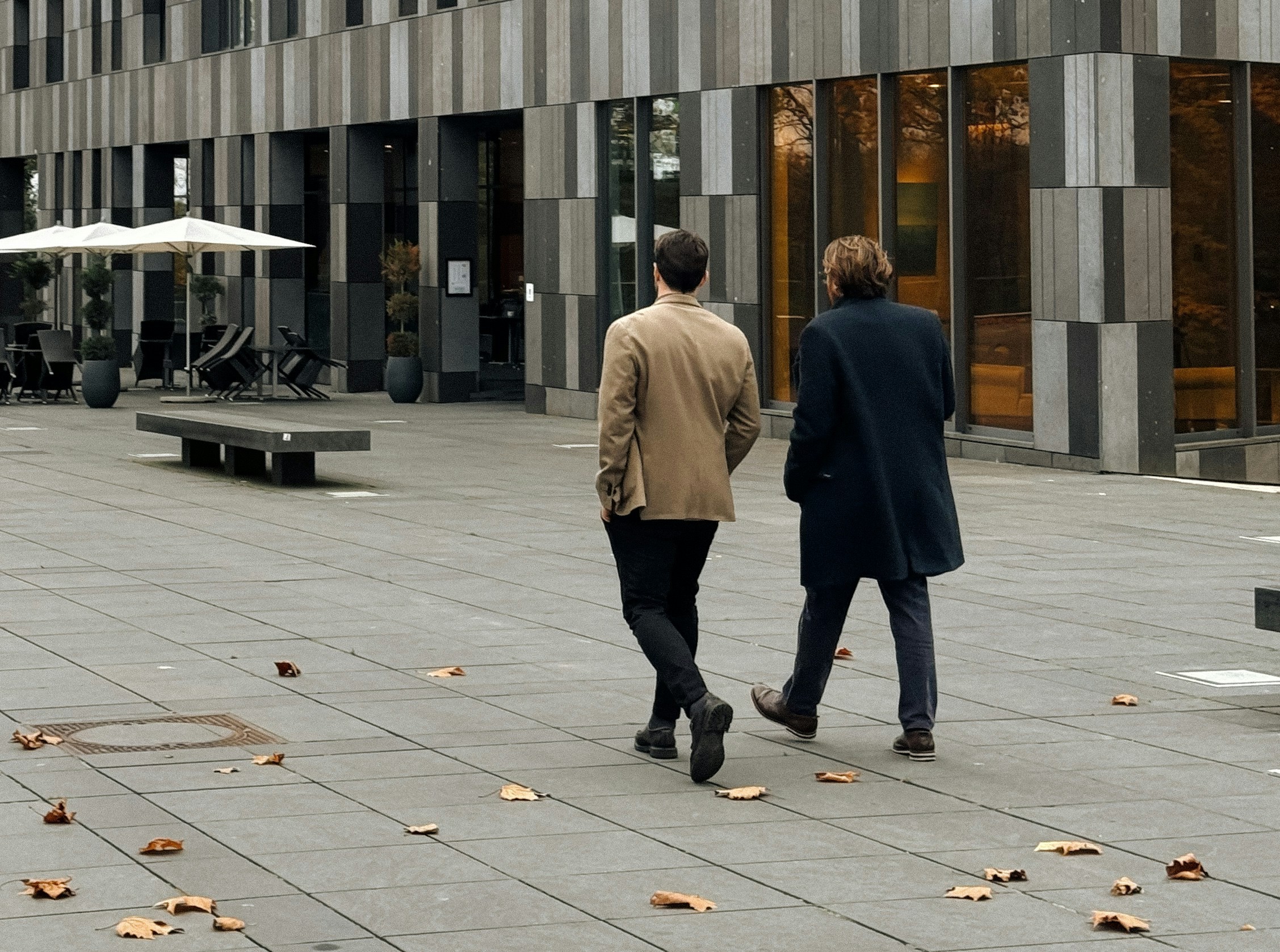 Twee mensen lopen naast elkaar in een zakelijke omgeving, als beeld voor een sparringpartner voor leidinggevenden.