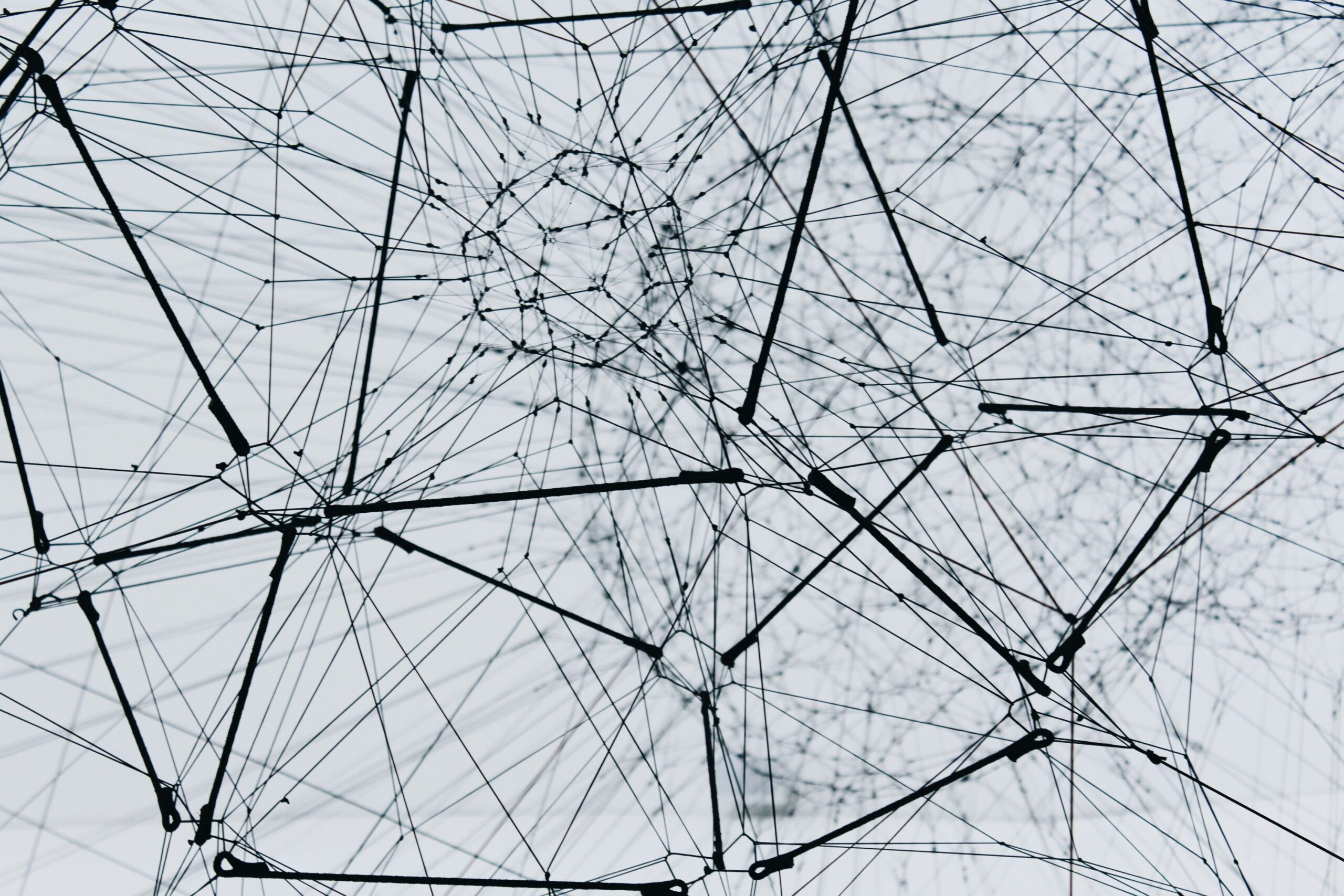 Een netwerk van dunne lijnen en staven die elkaar kruisen en verbinden in een complexe geometrische structuur.