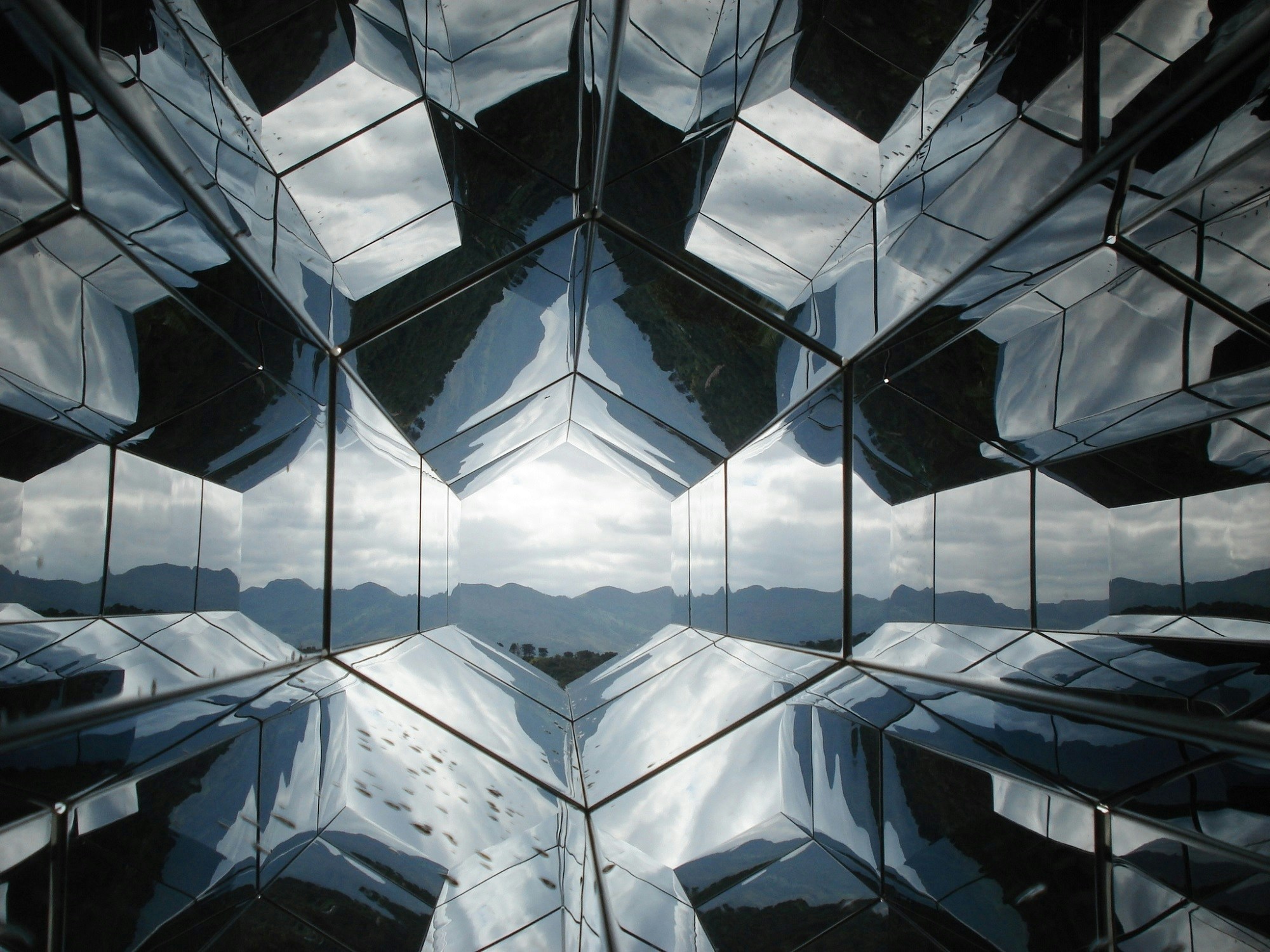 Geometrische spiegelingen in een glazen gebouw met verschillende zichtlijnen en reflecties.